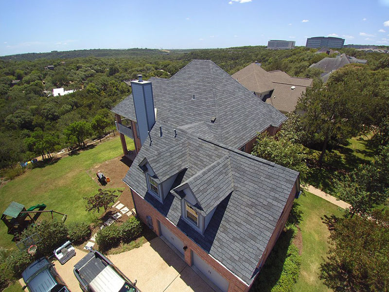 Residential roof project completed by Austintatious Roofing Company - brand new dark gray shingles installed on mid-class home